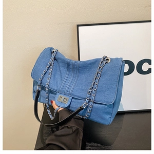 Detail of blue denim quilted bag with silver twist-lock and metal chain strap