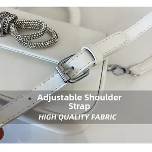 Detail of adjustable leather strap with silver buckle and rhinestone bow on white handbag