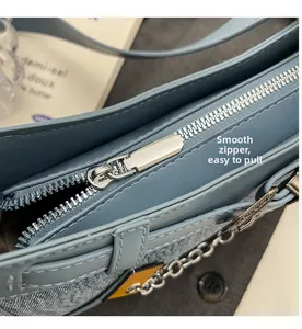 Detail der hellblauen Jeans-Umhängetasche mit glattem Silberreißverschluss und Metallkette