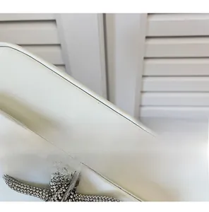 Detail showing high-quality white leather fabric and sparkling rhinestone bow buckle