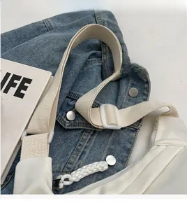 Détail du sac à bandoulière en nylon blanc avec sangle tissée réglable et boucle en plastique