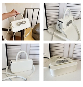 Detail view of white crossbody box bag with rhinestone bow and adjustable strap