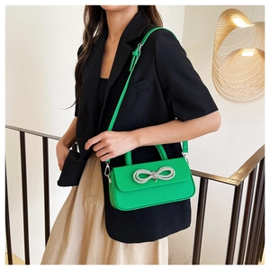 Close-up of vibrant green crossbody bag with a sparkling silver rhinestone bow detail