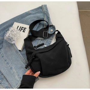 Détail du sac demi-lune noir en nylon avec bandoulière réglable et tirette tressée