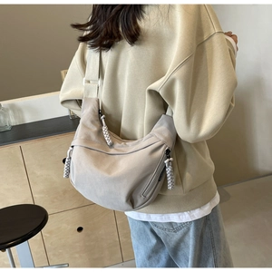 Détail du sac croissant beige avec tirette de fermeture tressée et large bandoulière