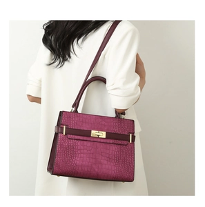 Magenta faux crocodile leather handbag with golden twist lock shown on model
