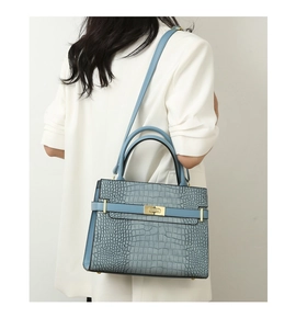 Blue crocodile embossed leather handbag with gold twist lock shown on model's shoulder