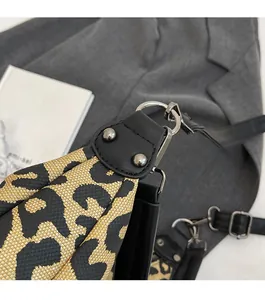 Detail of leopard print canvas bag featuring black leather trim and silver metal rivets