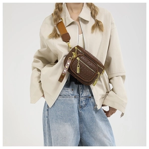 Quilted dark brown crossbody chest bag with wide woven strap and metal charms
