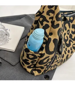 Close-up of functional side pocket on leopard print canvas crossbody bag showing storage