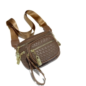 Quilted dark brown crossbody bag with triple zippers and wide woven strap on white background