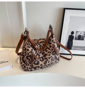 Detail of leopard print canvas bag with brown leather straps and metal zippers