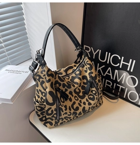Detail of stylish leopard print canvas tote bag with black leather handle and zipper pocket