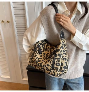 Close-up of leopard print canvas bag with leather strap and multiple zipper pockets