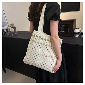 Cream knit tote bag with colorful accents shown in a modern cafe setting