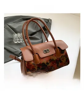Detail of vintage brown leather handbag featuring artsy patterns and woven rope handle