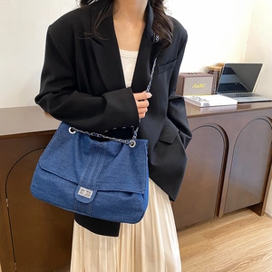 Deep blue denim chain bag for women with silver buckle shown on shoulder in daily life