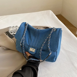 Quilted blue denim crossbody bag with silver chain strap and metal turn-lock closure