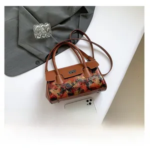 Detail view of vintage brown handbag with floral texture, top handle and crossbody strap