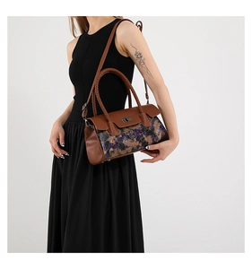 Detail of trendy purple floral crossbody bag with brown braided handle and gold metal twist lock