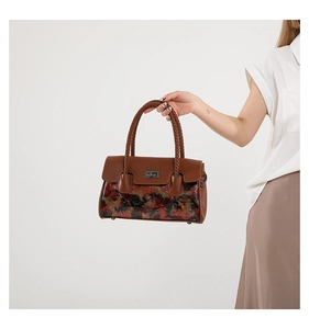 Detail of vintage brown leather handbag with tricolor weave and bronze clasp