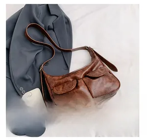 Detailansicht der braunen Vintage-Handtasche mit zwei Fronttaschen auf weißem Stoffhintergrund