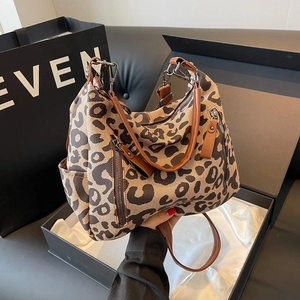 Leopard print canvas tote bag with brown leather handles and adjustable shoulder strap