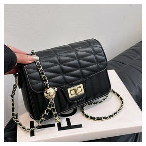 Detail of black quilted crossbody bag with gold twist lock and chain strap on box