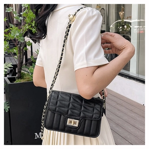 Detailed view of black quilted leather bag featuring gold twist lock and chain strap