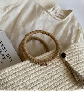 Close-up of beige woven tote bag with circular handles and decorative beaded tassels