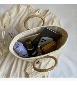 Flat lay of a woven tote bag showing interior capacity with essentials on a beige dress