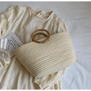 Detail of hand-woven cream tote bag with circular light brown grass handles for summer