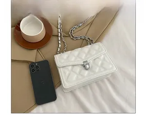 Detail view of white quilted chain bag on a blazer with elegant silver metal lock