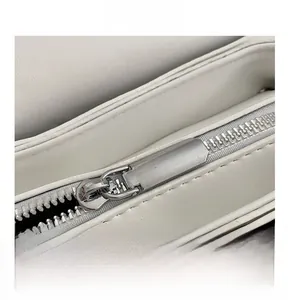 Macro view of a smooth silver zipper on a white quilted leather shoulder bag detail