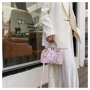 Close-up of pink snakeskin pattern shell bag with silver metallic texture and golden hardware