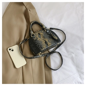 Detail of black shell bag with golden python texture on khaki blazer background
