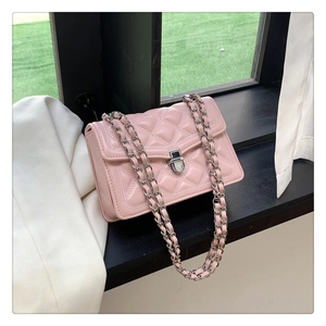 Pink quilted shoulder bag with silver chain strap and metal lock detail on windowsill