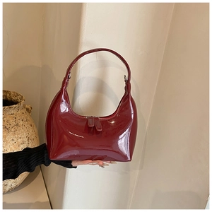 Dettaglio della borsa a mezzaluna in pelle verniciata bordeaux con doppia zip in metallo