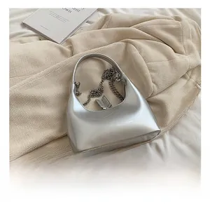 Dettaglio della borsa a mezzaluna in vernice argento con finitura metallica e catena