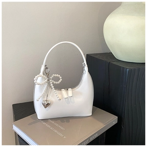 Dettaglio della borsa hobo bianca con ciondolo a fiocco di perle e cuore argento