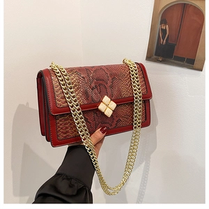 Close-up of red snakeskin texture crossbody bag with cream floral clasp and gold chain