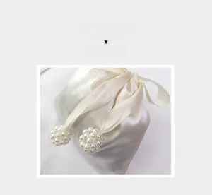 Close-up of cream satin drawstring bag with elegant pearl bead tassel detailing