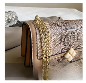 Detail of snake skin texture flap bag with champagne gold chain and floral buckle