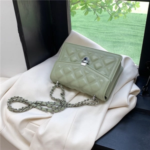 Chic mint green quilted chain bag with silver buckle on a beige blazer background