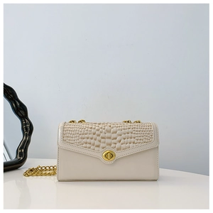 Dettaglio borsa a tracolla beige texture coccodrillo con catena dorata e chiusura a vite