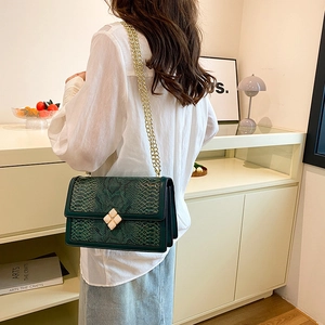 Green snake pattern chain bag with floral clasp shown on model in home setting