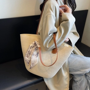 Large beige woven tote bag with brown leather straps and decorative bamboo print silk scarf