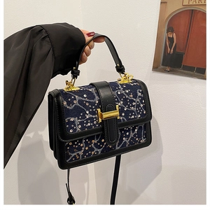 Detail of blue denim mini bag featuring sequin wave texture and golden H-shaped clasp