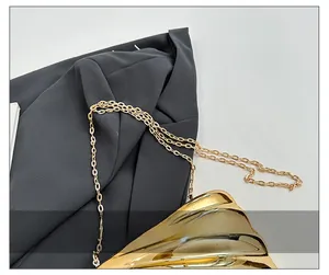 Detail of a golden shell-shaped textured bag with an elegant metal chain shoulder strap