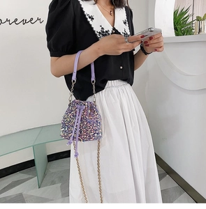 Close-up of purple sequin bucket bag featuring drawstring closure and gold chain strap